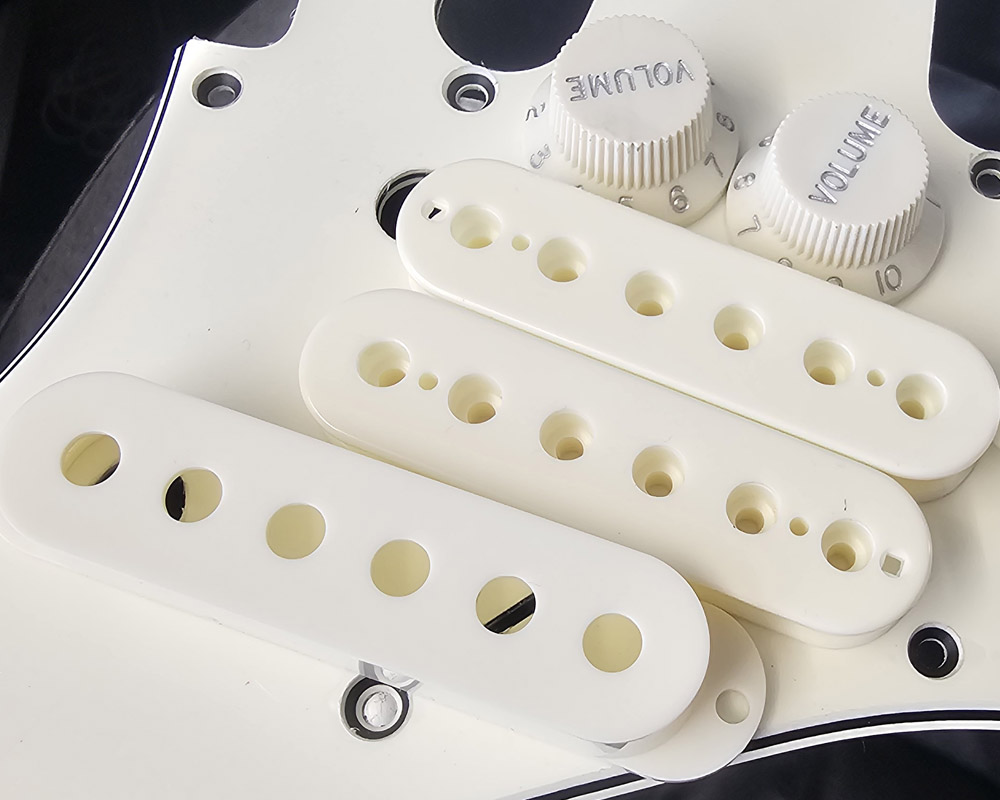 Parchment Humbucker Bobbins, Single Coil Cover, UFO knobs and TIp resting on a matching Stratocater pickguard